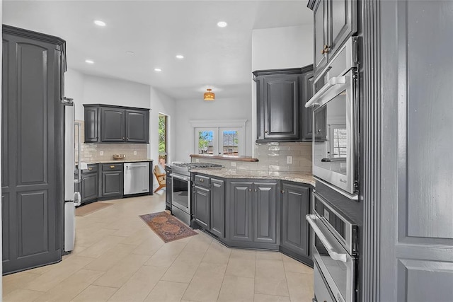 kitchen with appliances with stainless steel finishes, light stone counters, gray cabinets, recessed lighting, and decorative backsplash