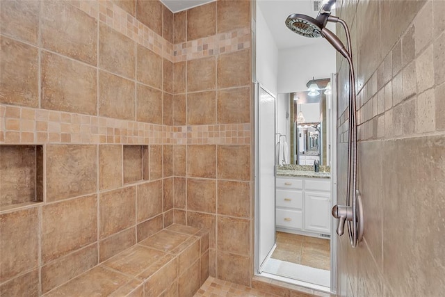 full bathroom featuring tile patterned floors, tiled shower, and vanity