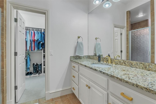 full bathroom featuring vanity, baseboards, a stall shower, and a spacious closet