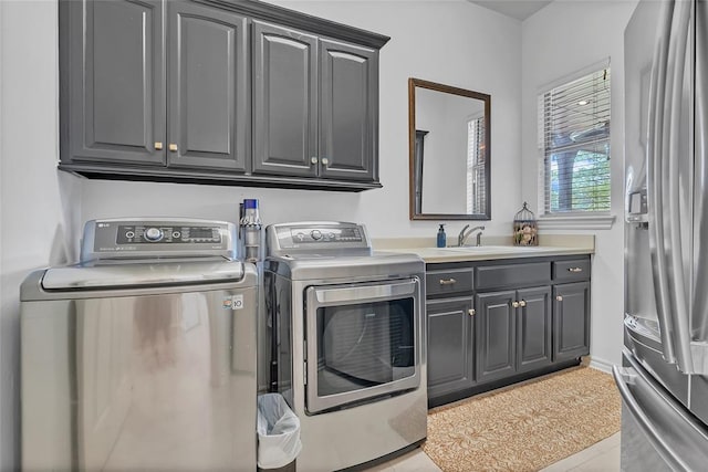 laundry room featuring a sink, cabinet space, light tile patterned floors, and washer and dryer
