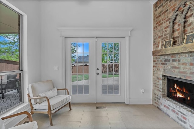 entryway with a brick fireplace, french doors, light tile patterned flooring, and visible vents