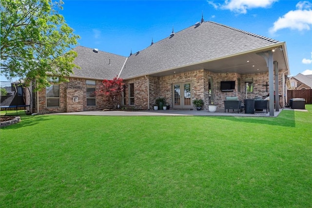 back of house with a yard, french doors, a shingled roof, and a trampoline