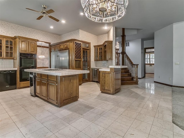 3601 Rena Dawn Ln, Edmond, OK 73013 - kitchen featuring backsplash, a center island, black appliances, tile counters, and wallpapered walls