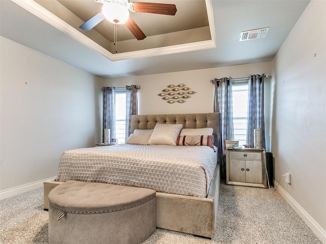 bedroom with a raised ceiling, multiple windows, carpet, and visible vents