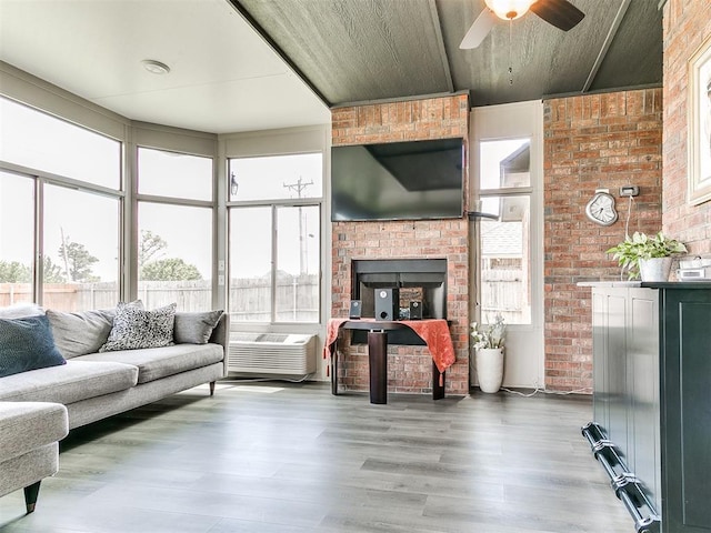 living room featuring brick wall, a fireplace, a ceiling fan, and wood finished floors