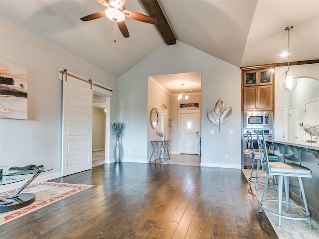 living room with a barn door, a ceiling fan, dark wood-style floors, and beamed ceiling