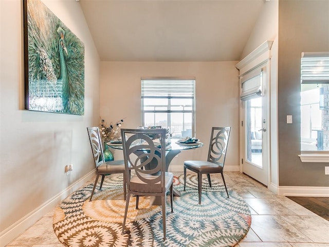 dining space featuring baseboards and vaulted ceiling
