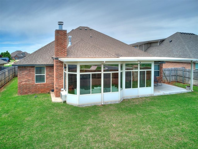 rear view of property with a shingled roof, a sunroom, a fenced backyard, a chimney, and a patio area