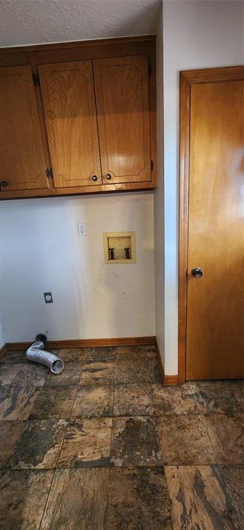 laundry room with washer hookup, cabinet space, stone finish floor, and baseboards