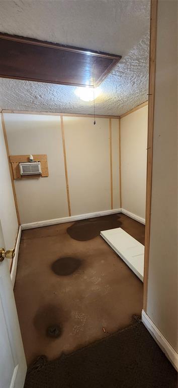 below grade area featuring baseboards, a textured ceiling, and a wall mounted AC