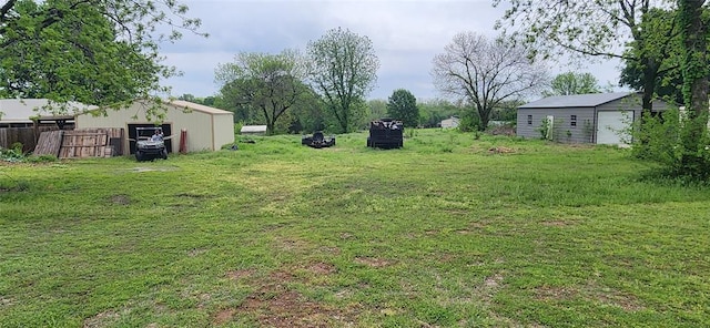view of yard featuring fence, a pole building, and an outbuilding