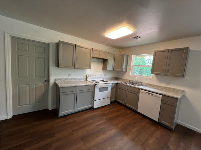 kitchen with a sink, visible vents, gray cabinetry, dark wood-style flooring, and white appliances