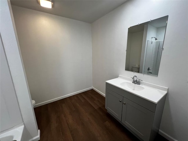 full bath with a shower, baseboards, toilet, wood finished floors, and vanity