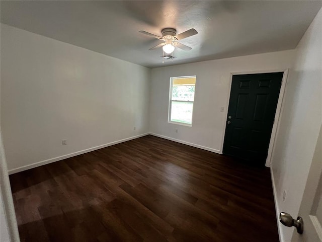 spare room featuring ceiling fan, dark wood-style floors, and baseboards
