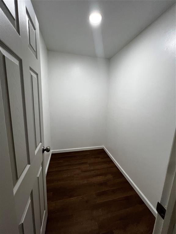empty room featuring dark wood-style floors and baseboards