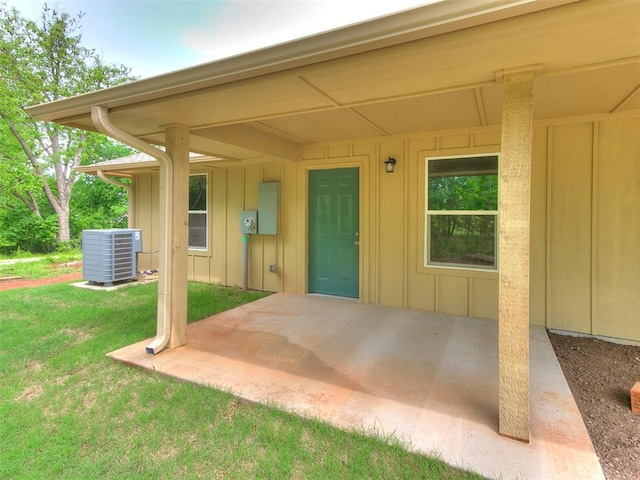 1823 E Rutgers Ave, Guthrie, OK 73044 - view of exterior entry featuring a patio, board and batten siding, central AC, and a yard