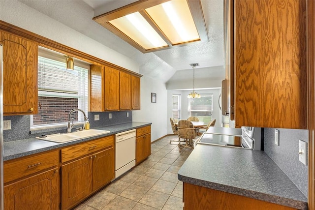 kitchen featuring a sink, dishwasher, decorative backsplash, light tile patterned floors, and dark countertops