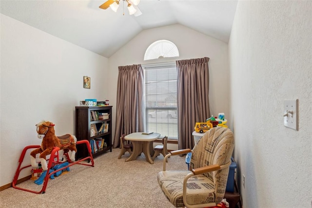sitting room with ceiling fan, lofted ceiling, a textured wall, and carpet floors