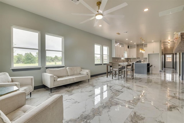 living area with ceiling fan, recessed lighting, marble finish floor, and baseboards
