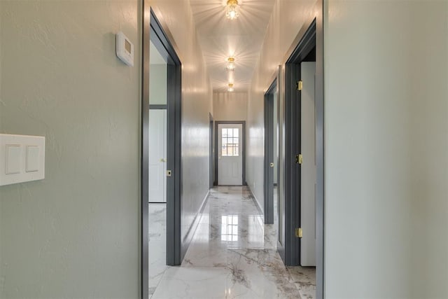 hallway featuring a textured wall and marble finish floor