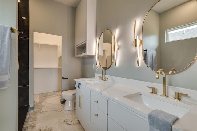 bathroom featuring toilet, marble finish floor, a sink, and double vanity