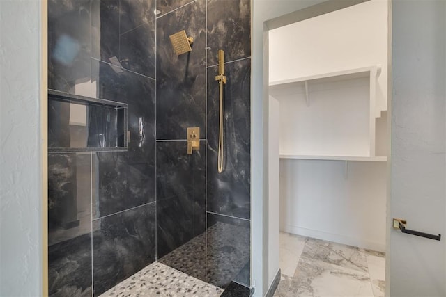 bathroom with baseboards, marble finish floor, and tiled shower