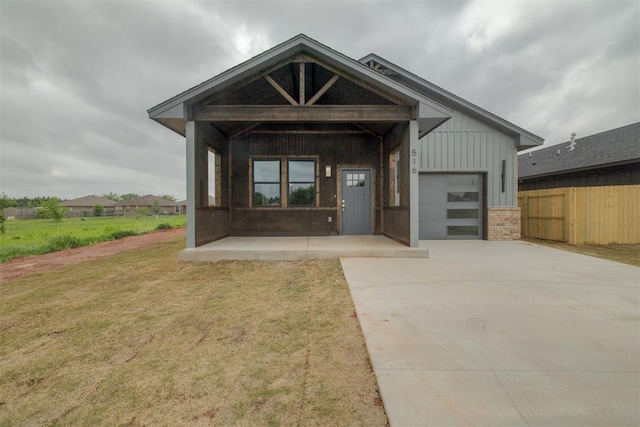 view of front facade with brick siding, fence, a garage, driveway, and a front yard