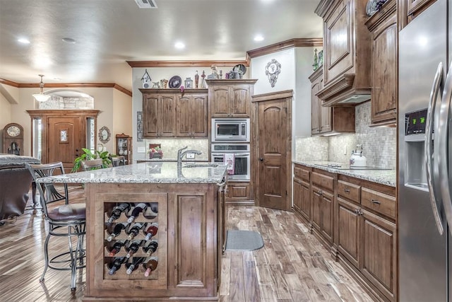 1400 S May Ave, Guthrie, OK 73044 - kitchen featuring stainless steel appliances, a breakfast bar, light wood finished floors, decorative backsplash, and crown molding