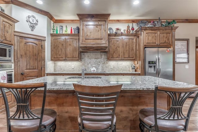 1400 S May Ave, Guthrie, OK 73044 - kitchen featuring appliances with stainless steel finishes, decorative backsplash, light stone countertops, a sink, and a breakfast bar