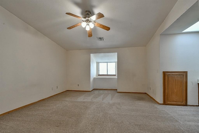 spare room with a ceiling fan, visible vents, light colored carpet, and baseboards
