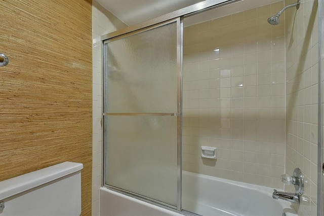 full bath with combined bath / shower with glass door, wood walls, and toilet