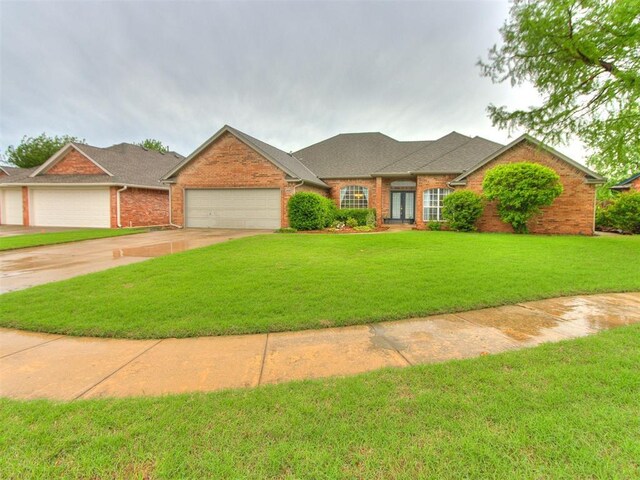 view of front of house featuring roof with shingles, an attached garage, brick siding, a front yard, and driveway