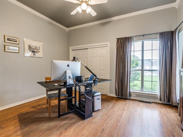 office area featuring a ceiling fan, visible vents, baseboards, light wood finished floors, and ornamental molding