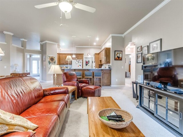 living area with light colored carpet, ornamental molding, baseboards, and a ceiling fan