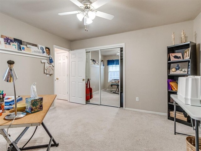 office space featuring baseboards, light carpet, and a ceiling fan