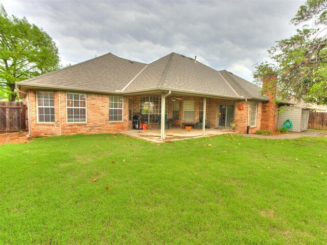 rear view of property with a patio, roof with shingles, fence, and a yard