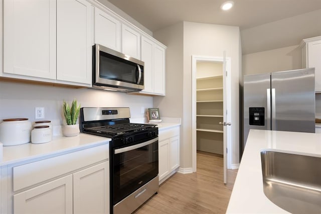 kitchen featuring recessed lighting, stainless steel appliances, light wood-style flooring, light countertops, and white cabinets