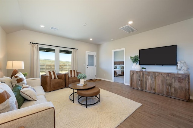 living room featuring baseboards, visible vents, wood finished floors, and recessed lighting