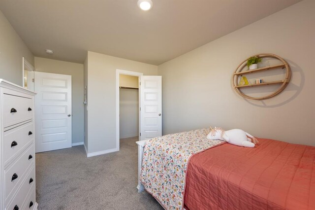 bedroom with a walk in closet, baseboards, and light carpet