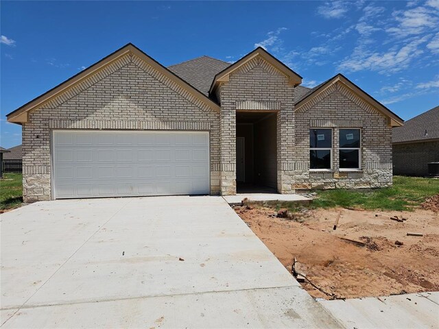 2412 Kathleens Xing, Yukon, OK 73099 - view of front of home featuring brick siding, concrete driveway, an attached garage, and stone siding