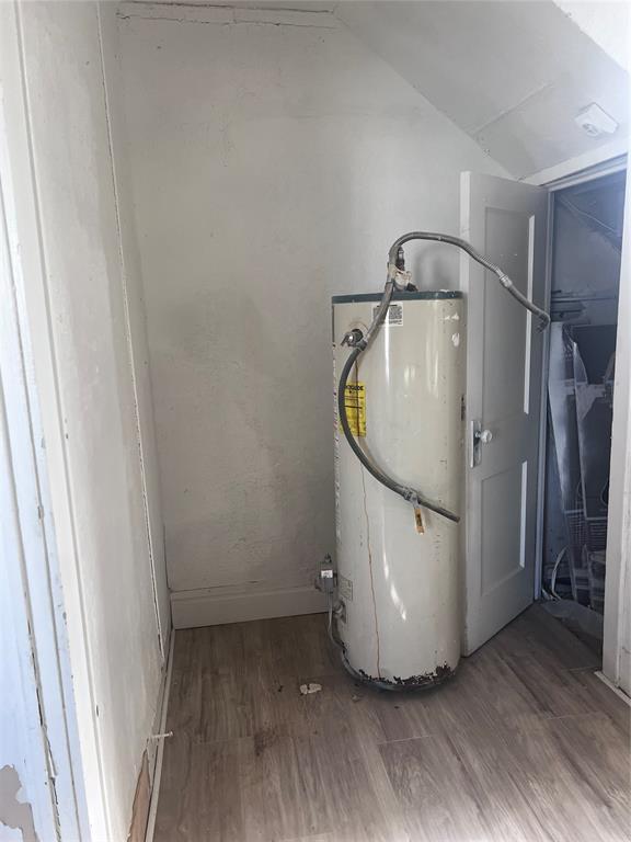 washroom featuring water heater, wood finished floors, and baseboards