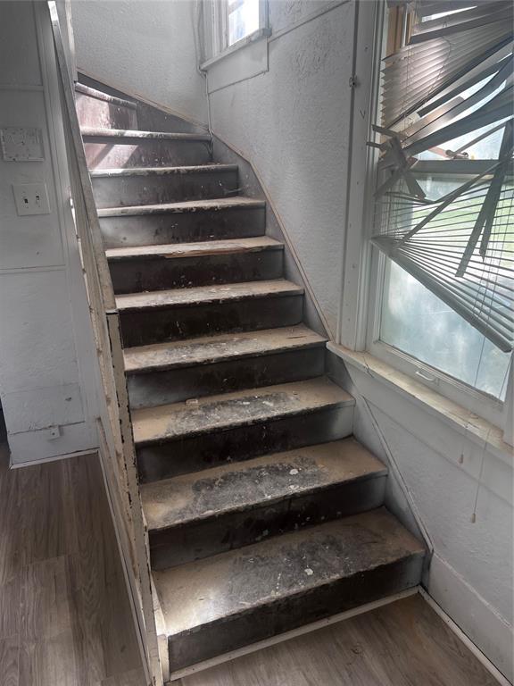 stairs with a textured wall, wood finished floors, and baseboards