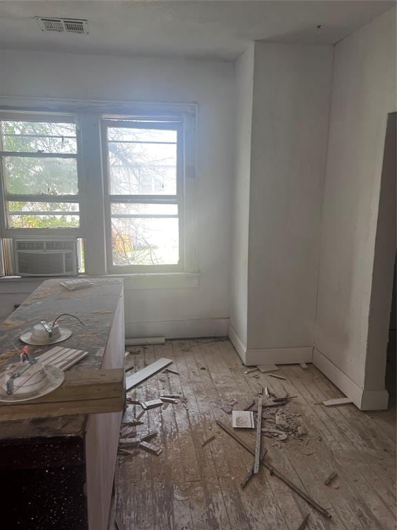 interior space featuring light wood-style floors, cooling unit, visible vents, and baseboards