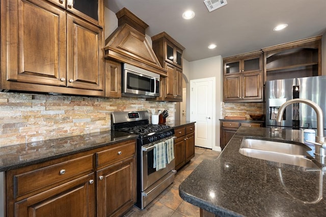 kitchen featuring visible vents, appliances with stainless steel finishes, tasteful backsplash, a sink, and dark stone counters