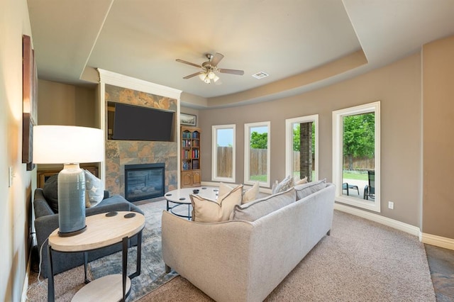 living room with visible vents, baseboards, ceiling fan, built in shelves, and a tiled fireplace