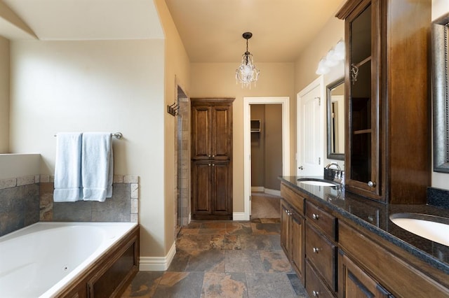 bathroom with a sink, double vanity, baseboards, stone finish flooring, and a bath