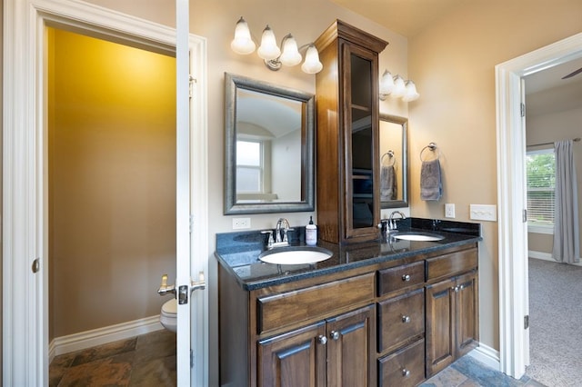 full bathroom featuring baseboards, a sink, and double vanity