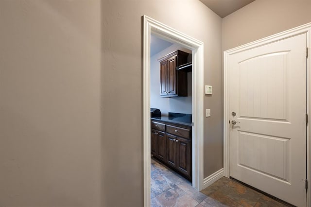 corridor with baseboards and stone finish flooring