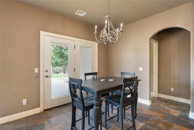 dining space featuring a notable chandelier, arched walkways, stone tile floors, baseboards, and visible vents