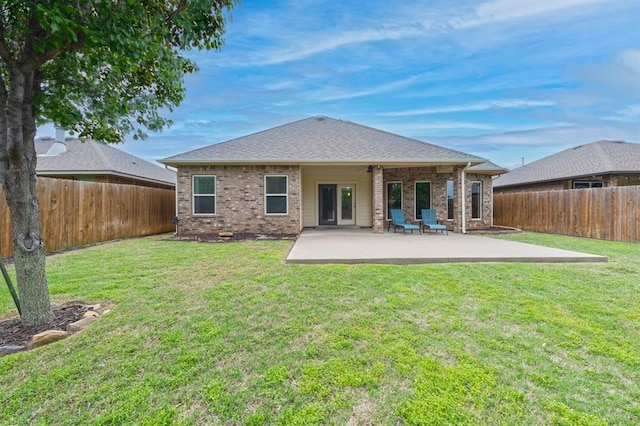 back of property with a lawn, brick siding, a fenced backyard, and a patio area